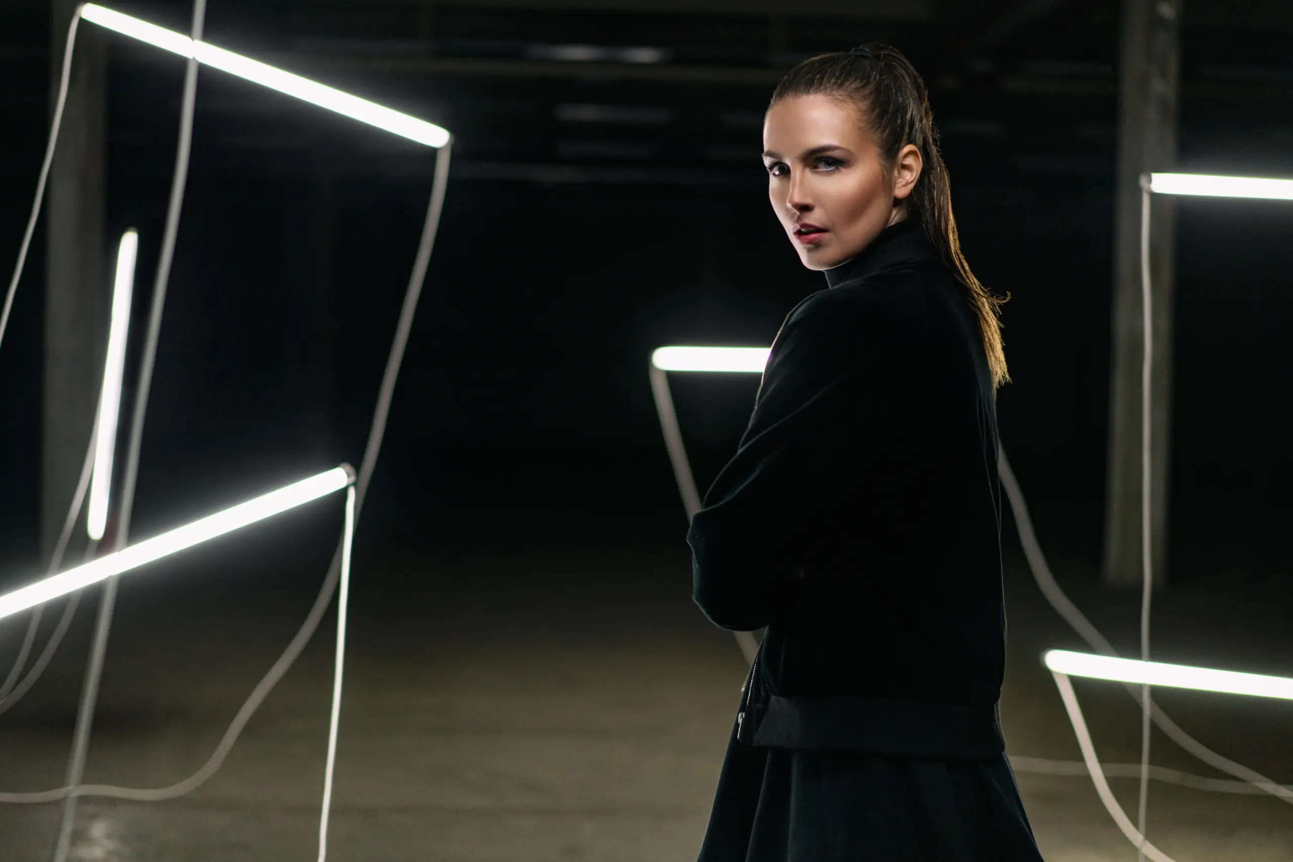 fashion photography of a model in industrial warehouse with neon tubes