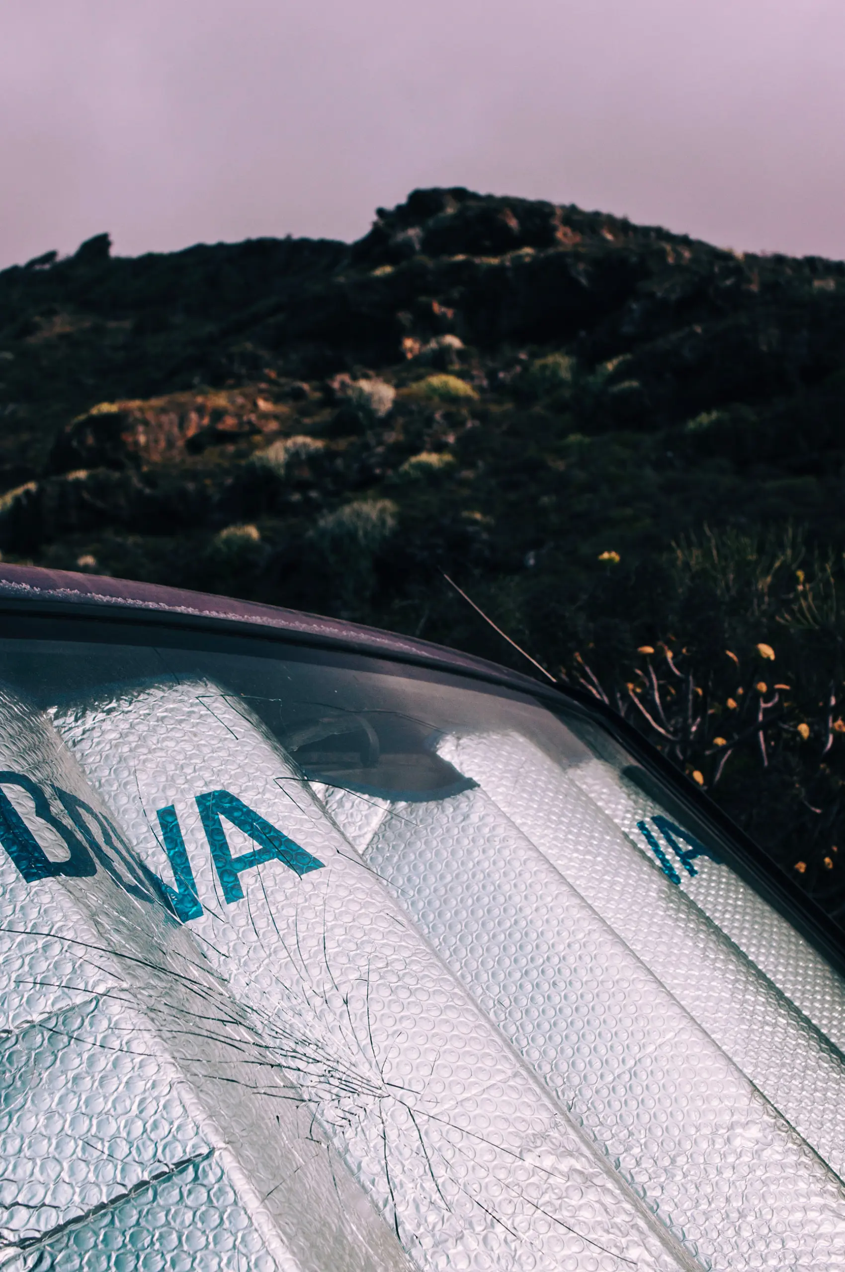 still photo of windscreen of a parked car in front of hill