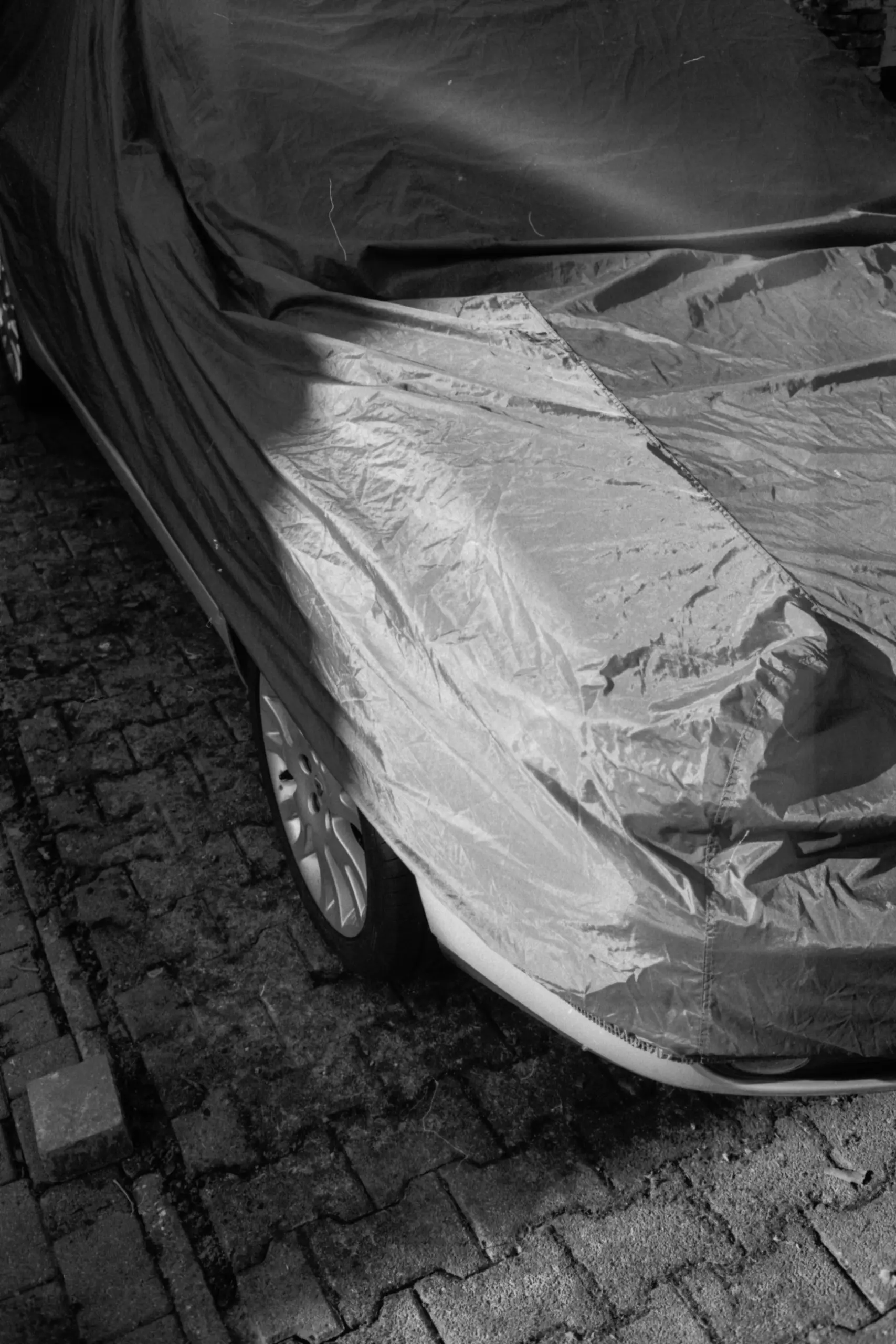 architecture photography of a car under a textile hood black and white, analog photography